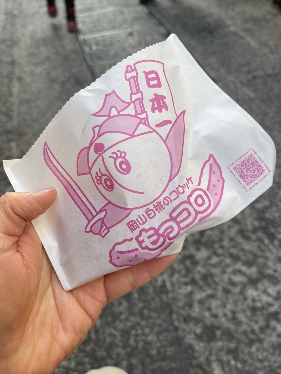 袋に入ったコロッケを左手で持っています。