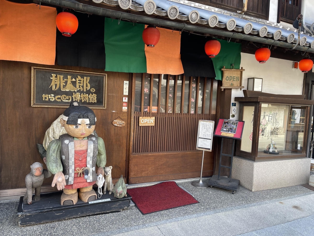 入り口は引き戸で、入り口の横にハリボテのような桃太郎があります。軒先に赤提灯がぶら下がっています。