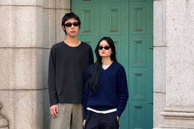緑の扉を背景にMODERN CLASSICのサングラスを着用したモデル2人