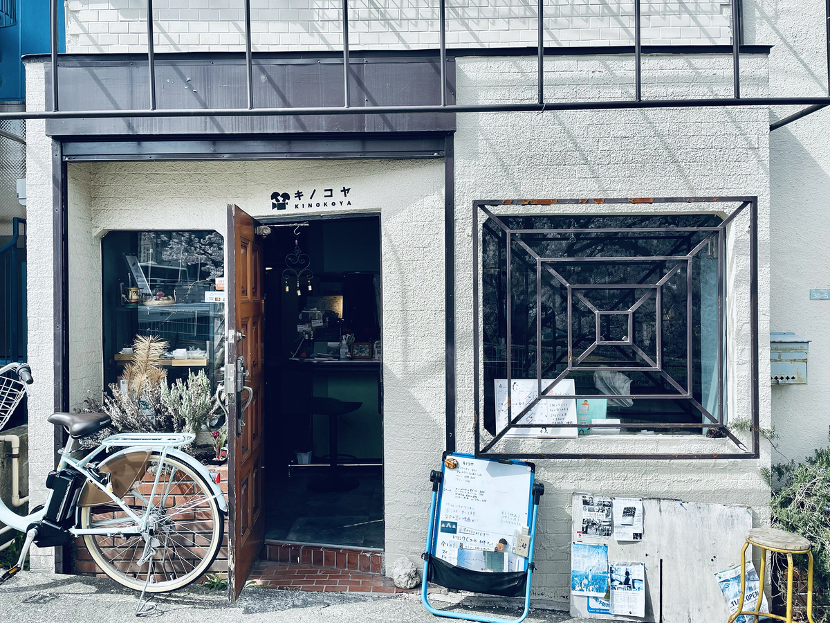 店先の自転車、開け放されたドア、大きな四角い窓に不思議なデザインの鉄格子。