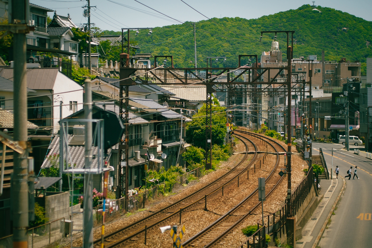 民家と道路に挟まれた、緩いカーブを描く線路。