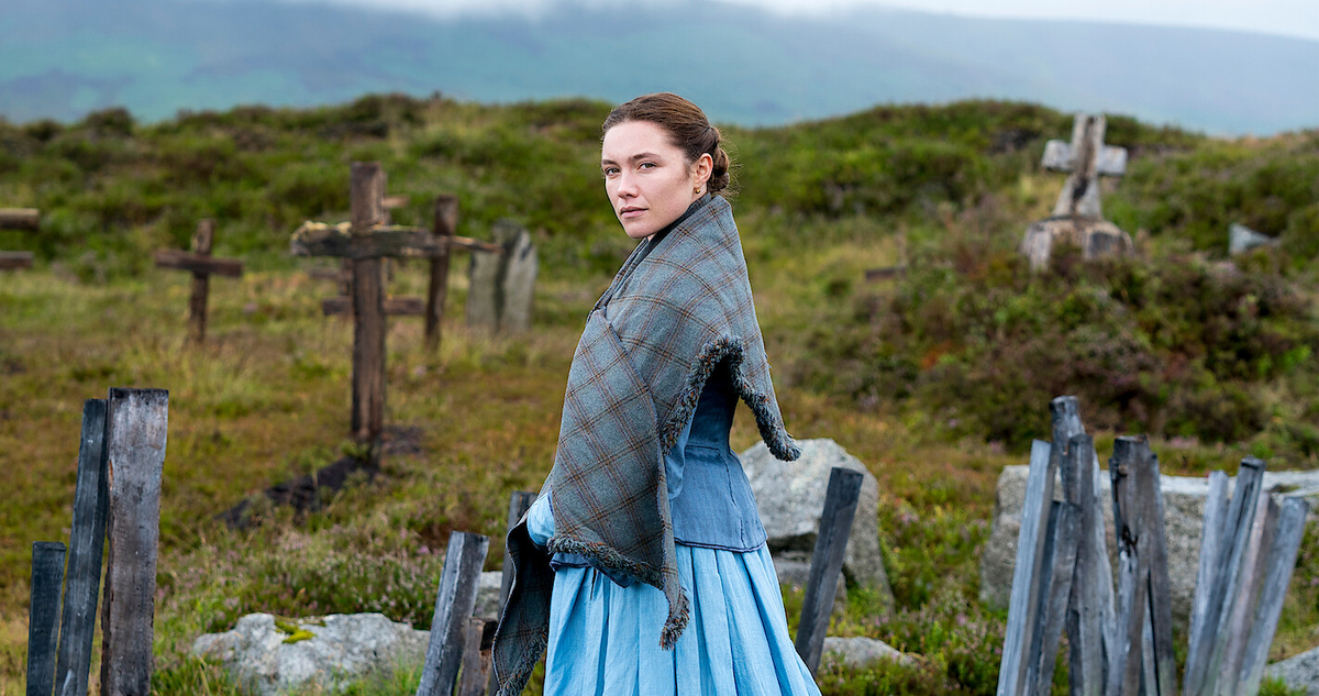 木製の十字架が立ち並ぶ墓場を背に、こちらに振り返るフローレンス・ピュー。