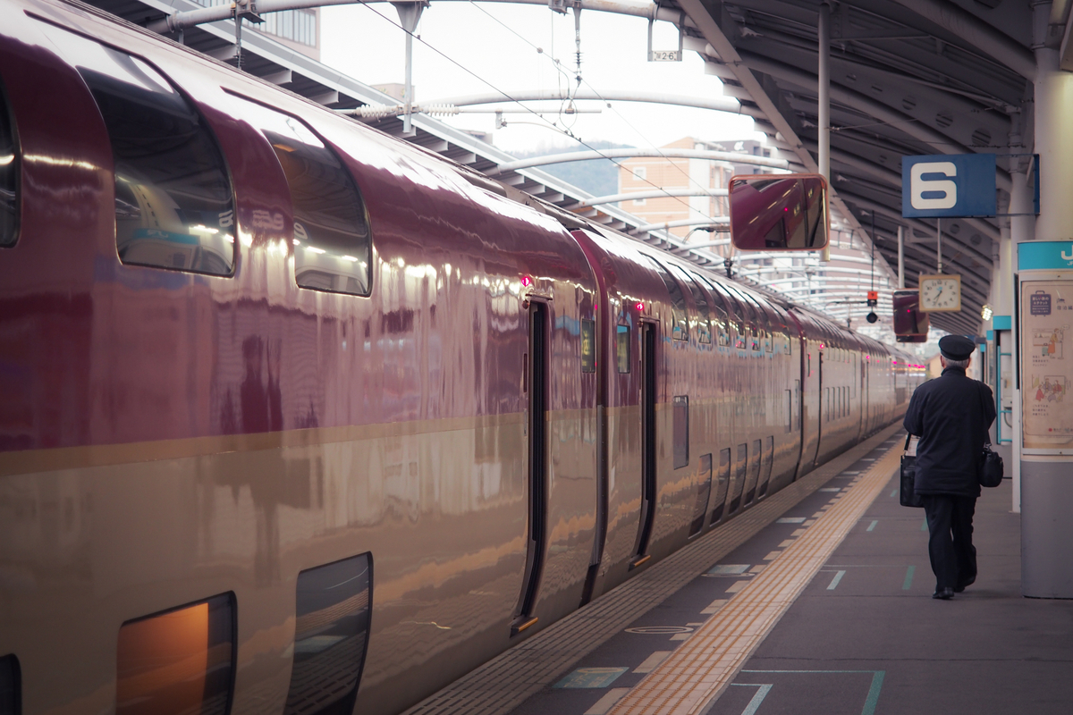 駅ホーム。停車中のサンライズと、歩いてゆく車掌さん、もしくは運転手さん。