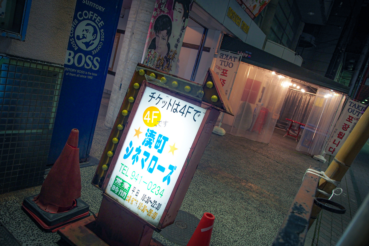 「チケットは4Fで」と書かれたシネマローズの看板と、その奥に韓国屋台のテント。