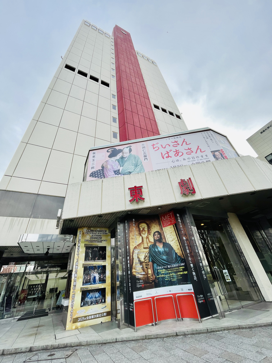 東劇の外観。天まで伸びる松竹本社ビル（かなり年季の入った、白と赤の建物）の一階部分に東劇のエントランス。まさしく「昔の映画館」の佇まい。しぶすぎる。