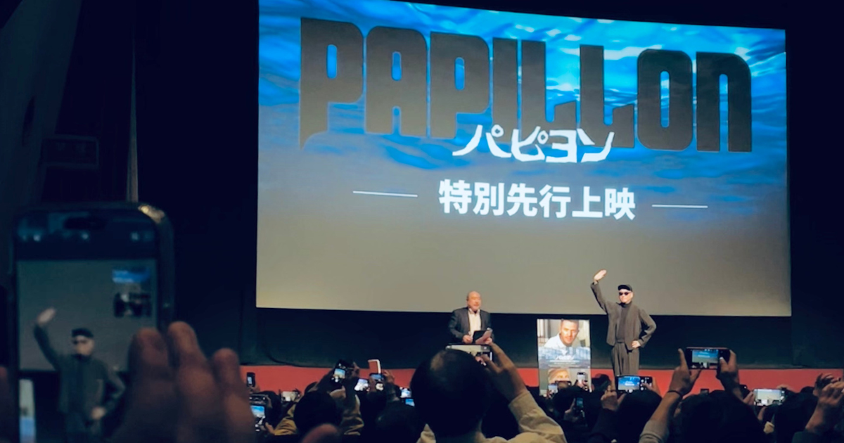 アフタートーク後のフォトセッションタイムに撮った写真。映画ロゴが投影された東劇の舞台上には、手を挙げてポーズをとる宇多丸さんと、聞き手の方。沢山のスマホが向けられている。