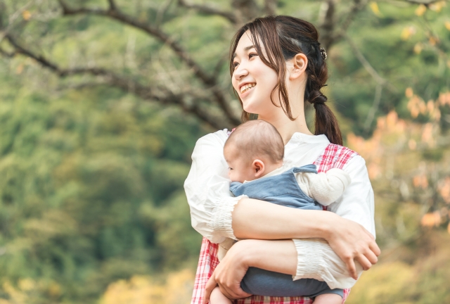 赤ちゃんを抱えて、遠くを眺める女性