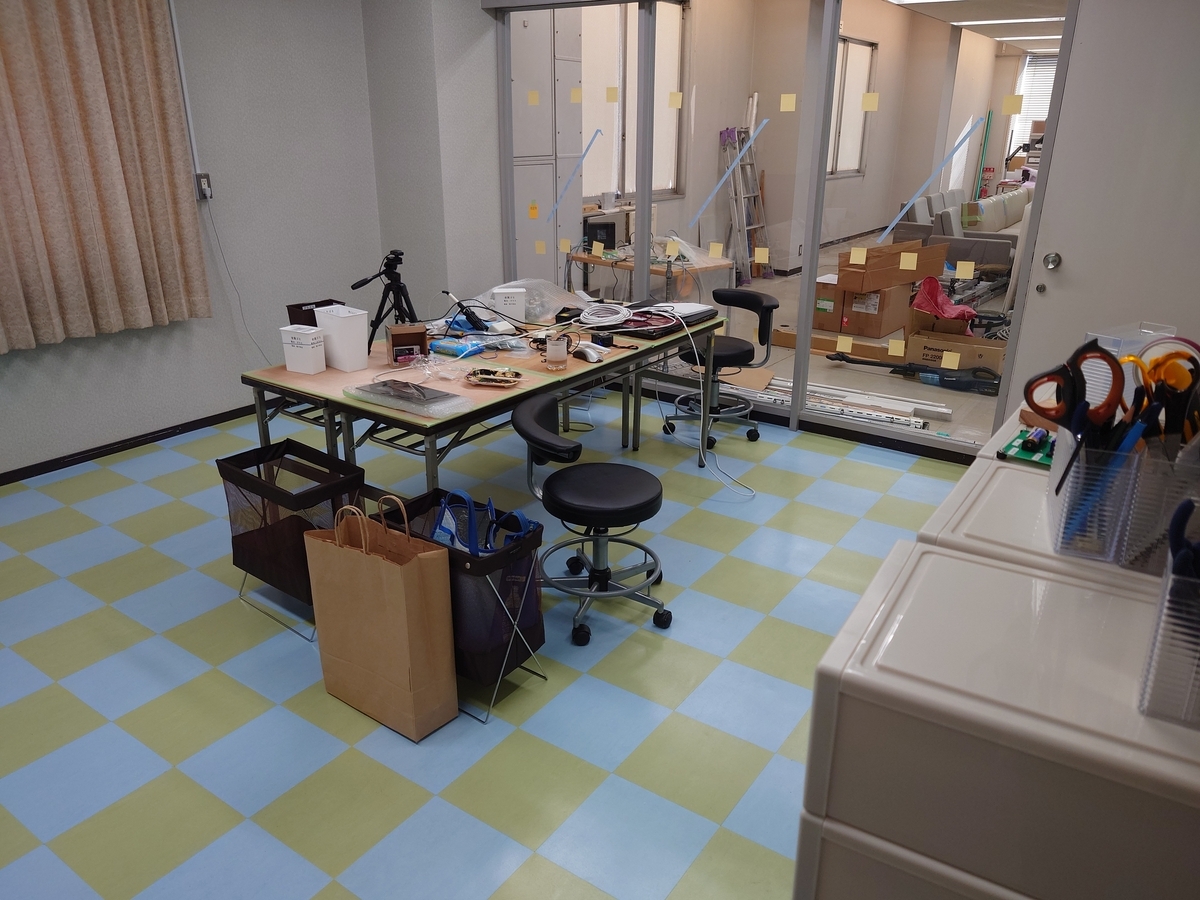 部屋の中央に置かれた机の上にハンダゴテや照明が置かれています．