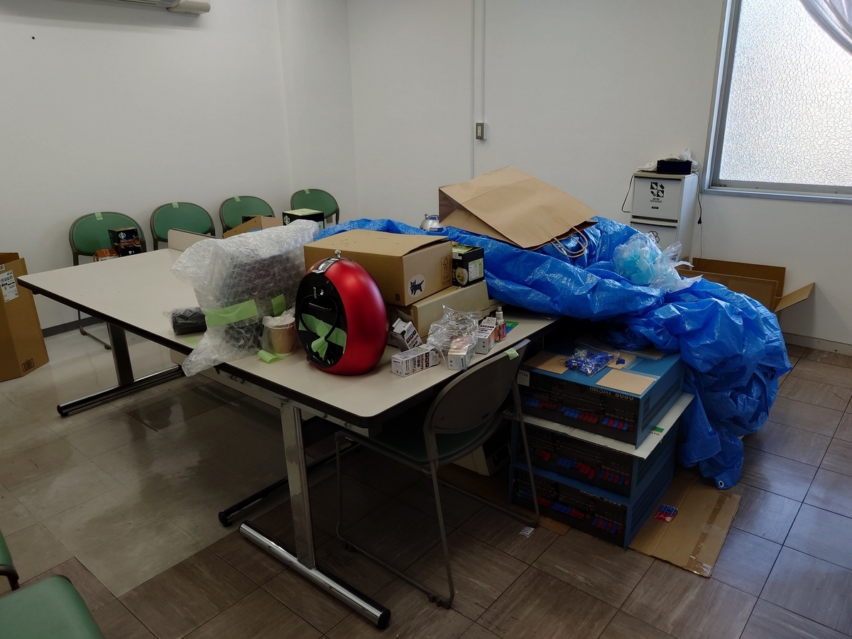 会議室の中心に寄せられた机にバリスタや文房具等が置かれています．