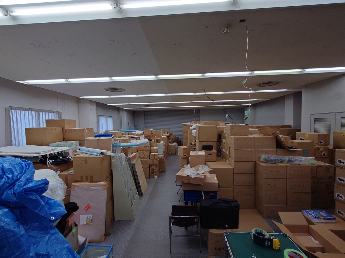 元銀行の窓口業務を行なっていた広い部屋にぎゅうぎゅうにダンボール箱が押し込められている．