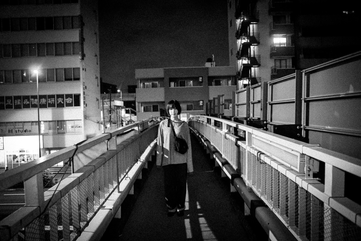 夜の歩道橋に立つボブヘアの女性
