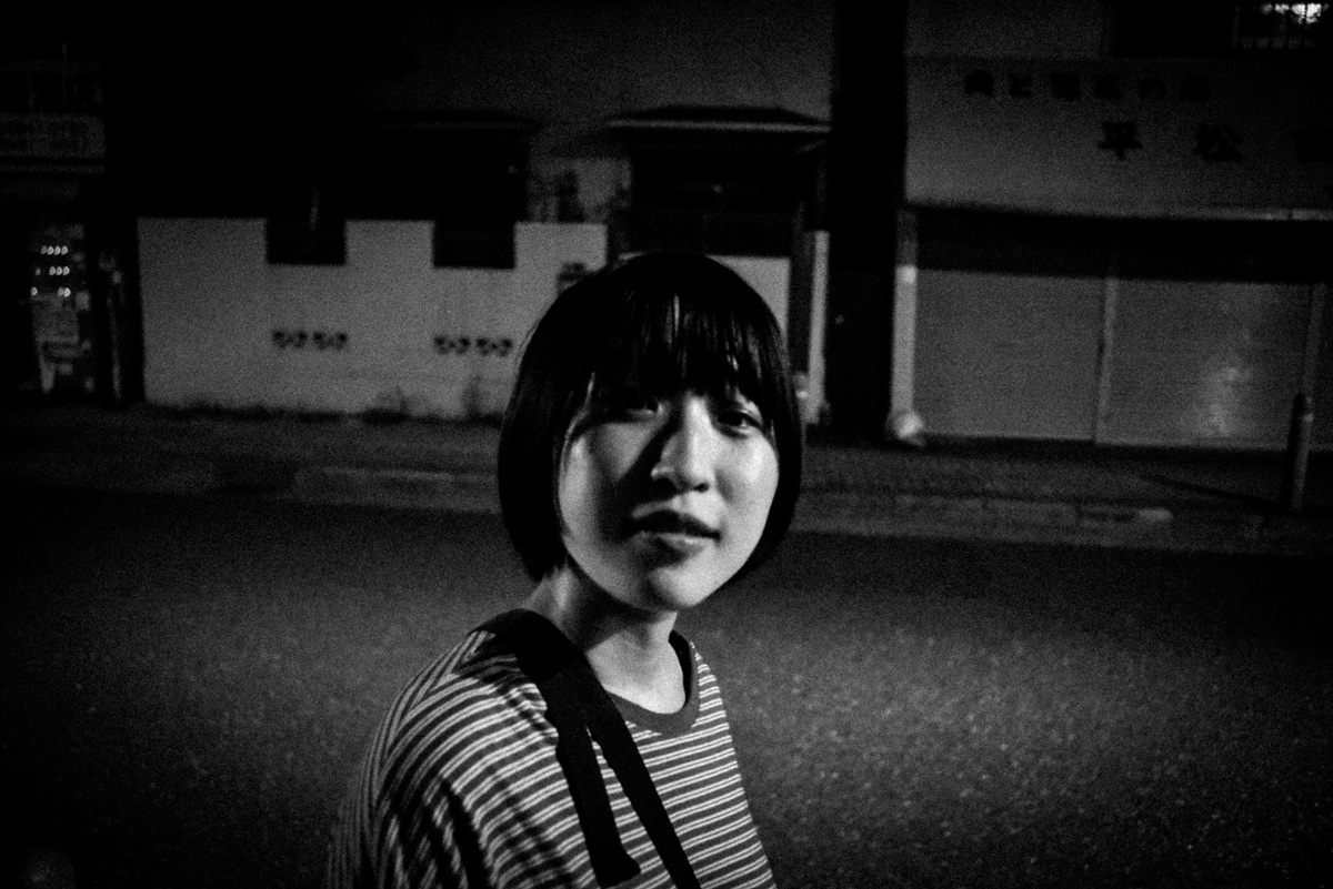 夜の街でカメラを見つめるボブヘアの女性