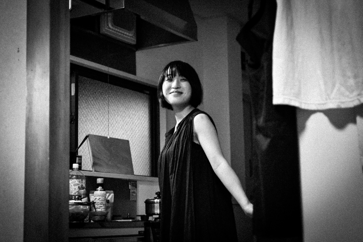 台所で目を閉じて微笑む黒い服の女性