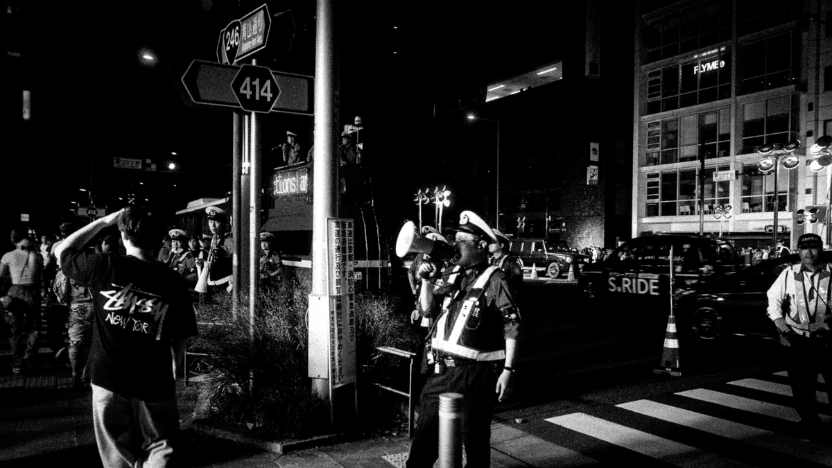 夜の交差点で群衆を誘導する複数の警察官