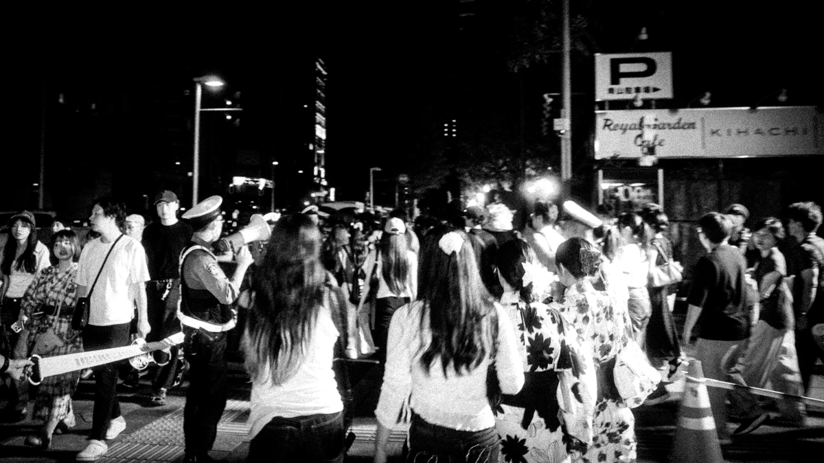 夜の交差点に立つ警察官と浴衣姿の人々