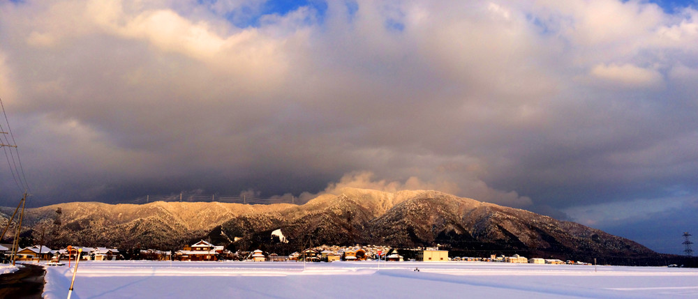 春の雪の七尾山の夕照