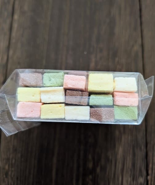 濃い板張りの上にある淡いカラフルな和菓子の側面