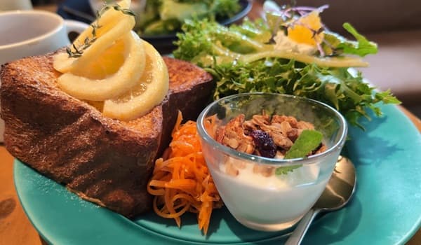 厚切りの焼いた食パンの上のシロップレモンとサラダとヨーグルト