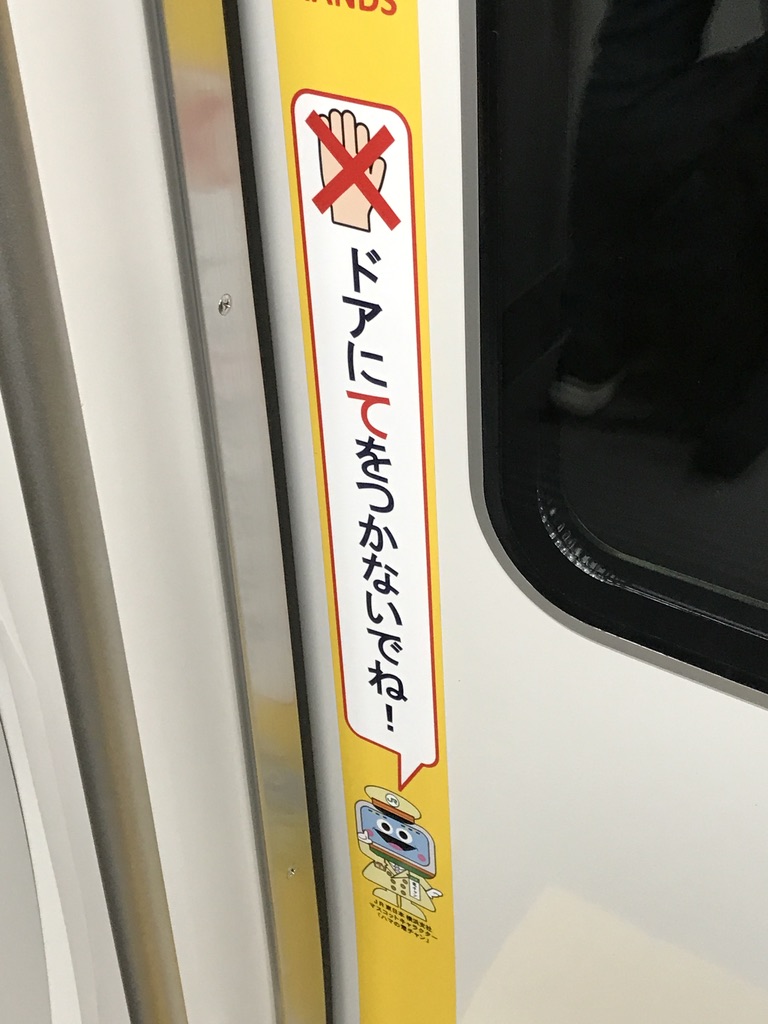 E235系1号車ドアに貼られた、ドアにご注意のシール(2020/12/21)