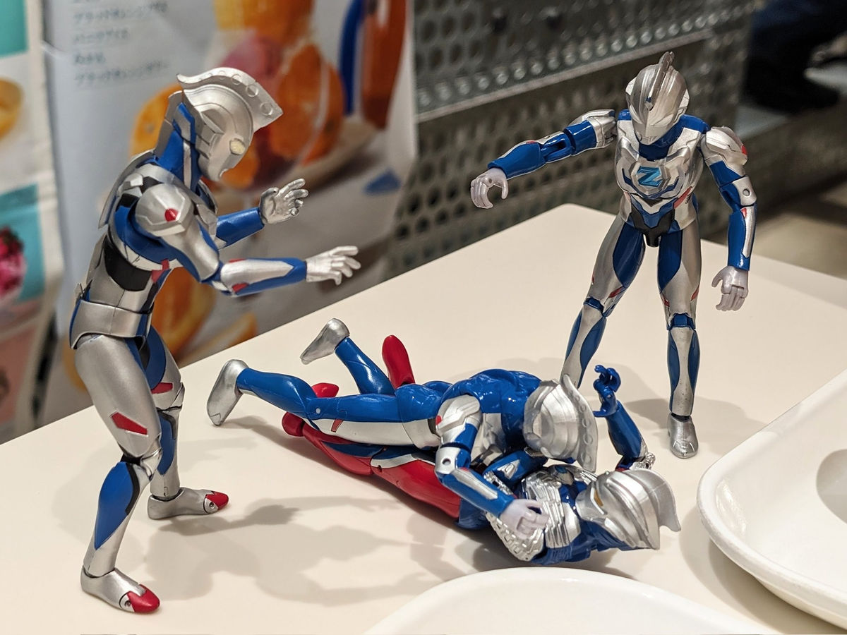 ä»°åãã«ãªã£ããŒãã®äžã«ã®ãããã£ãŠæ±ãã€ããŠãããŒãããã¢ãŒãã®ãŒãããšãããäžäººã®ã¢ã¯ã·ã§ã³ã®ãŒããããäž¡åŽã«ç«ã£ãŠæ
ãŠãããã«ãããèŠãŠããã