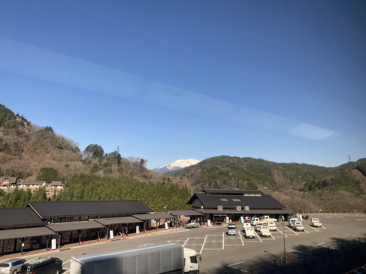 晴れた山あいから覗く御嶽山。手前に道の駅(?)がある。