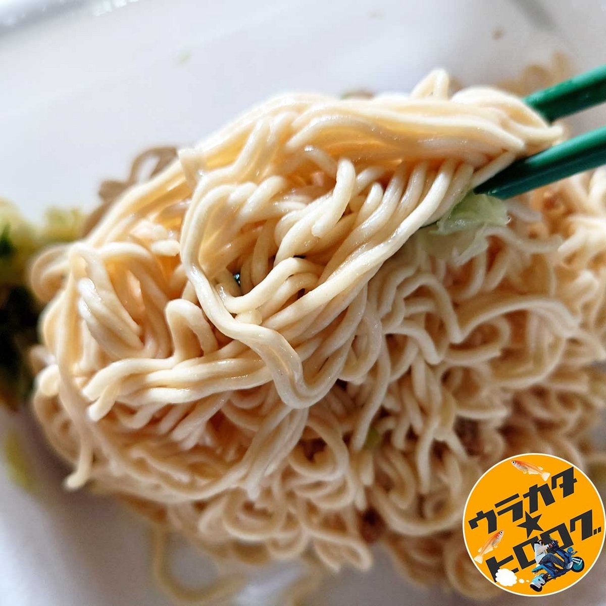 マルちゃん焼そば(インスタント版)の茹であがった麺に特製油を回しかけた後にお箸を使用して混ぜている様子の写真