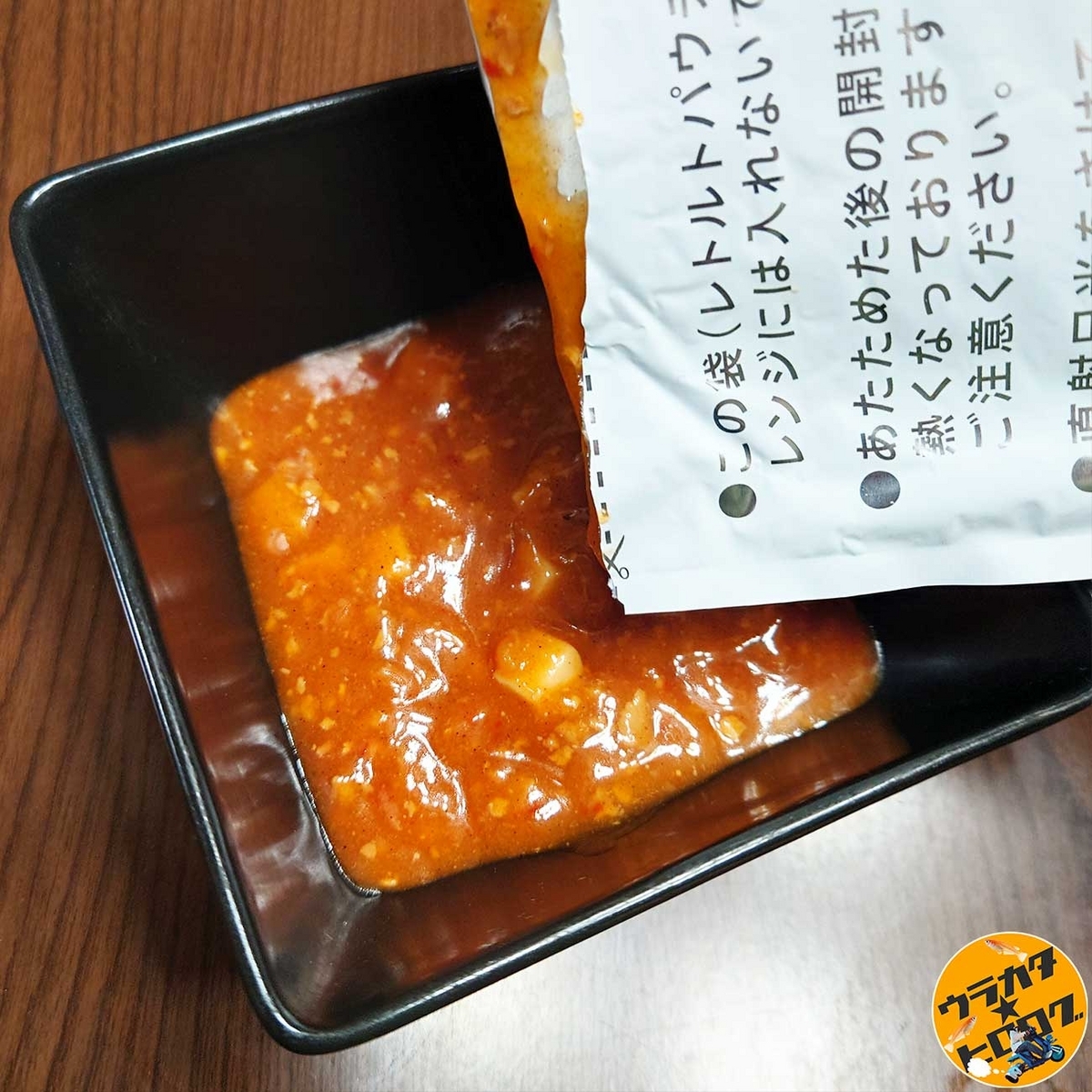 マルハニチロの金のどんぶりシリーズ”四川風麻婆丼”のパウチを開封して耐熱容器に移している様子(筆者撮影)