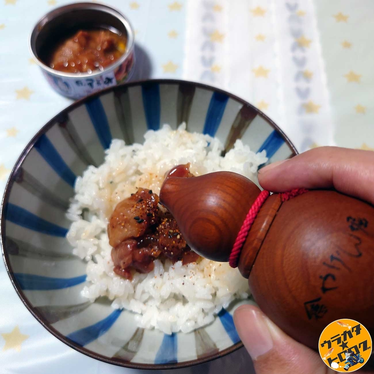 やげん堀の七味をホテイの焼き鳥に振りかけている様子(筆者撮影)