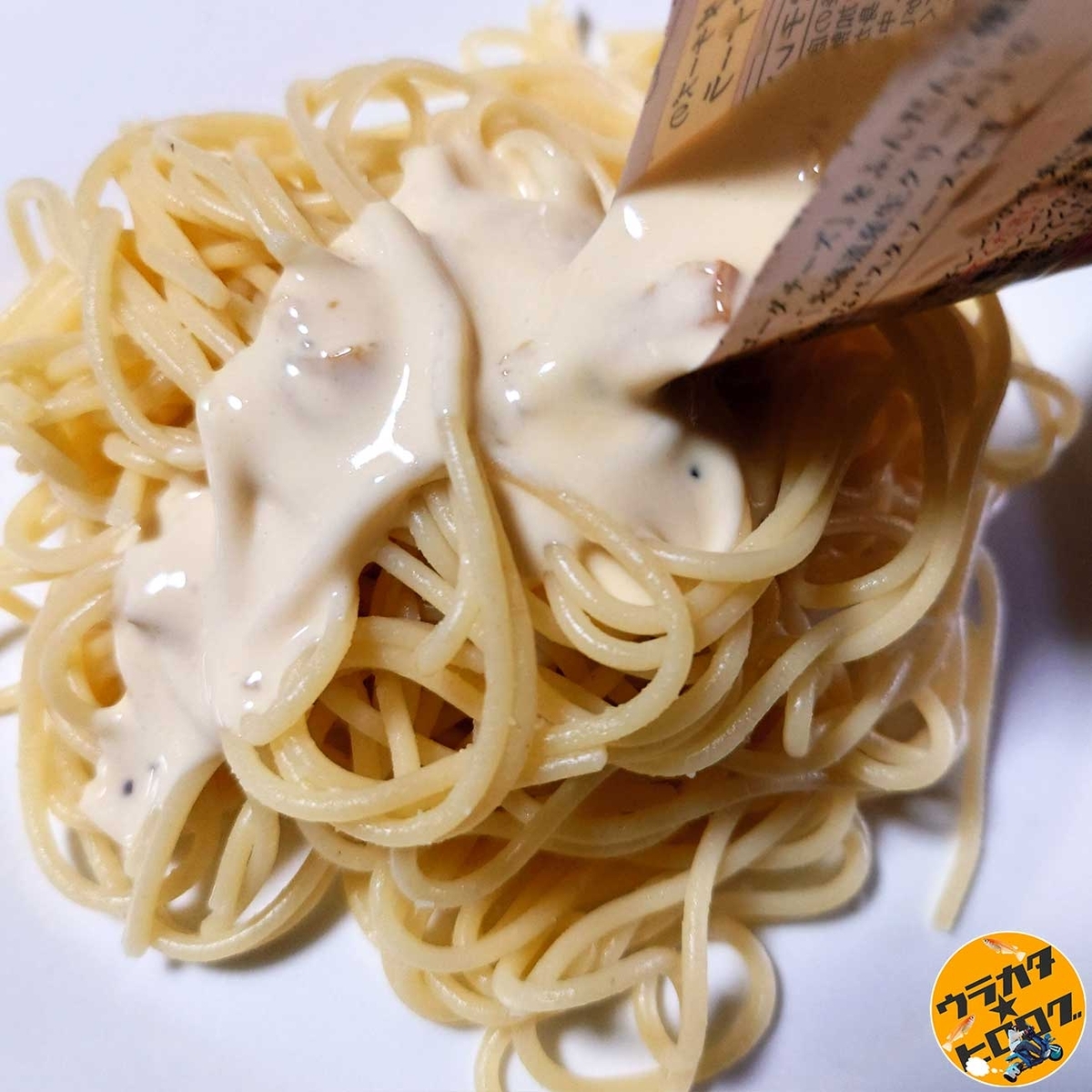 創味ハコネーゼ 生クリームとゴーダチーズの濃厚カルボナーラのソースをパスタにかけているシーン(筆者撮影/写真)