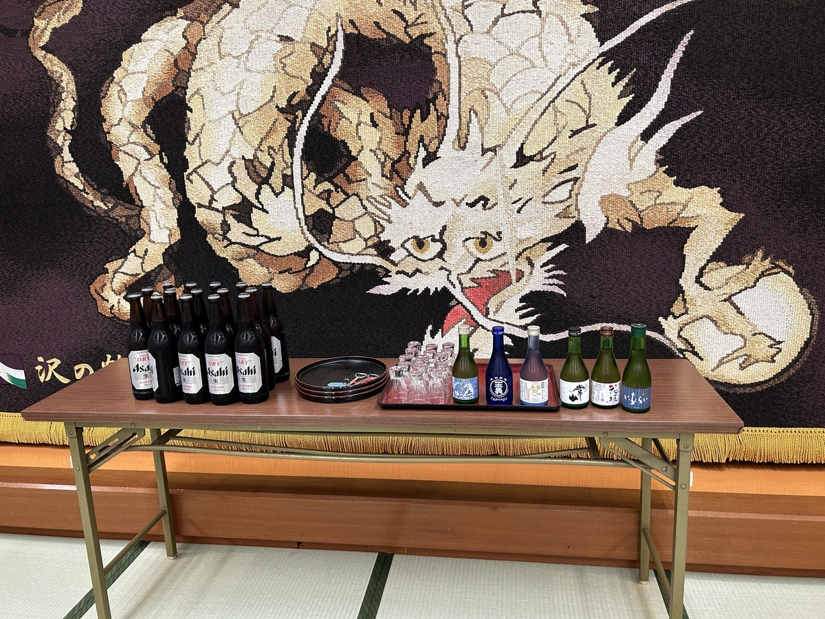 ビールや日本酒の瓶が並んでいる。後ろには龍の絵が描いてある幕がある