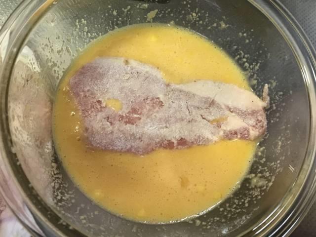 小麦粉を落とした豚肉を溶き卵にくぐらせる