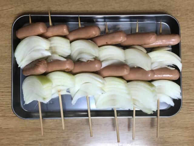写真:ウインナーと玉ねぎを串に刺す
