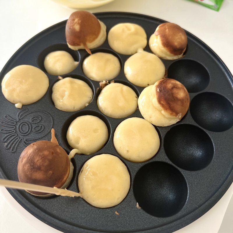 たこ焼き器でベビーカステラをひっくり返している様子。親子で楽しめるおやつ作り