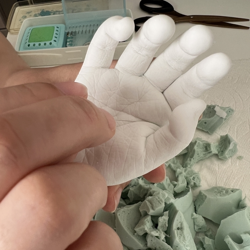 2歳児の手形をきれいに仕上げるために針でかたと~るを取り除いている作業写真。