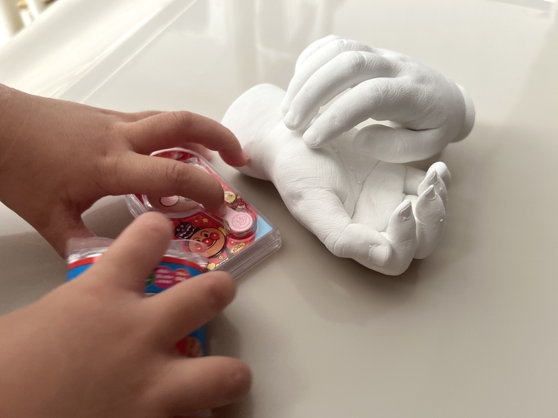 完成した石膏手形とそれを怖がる娘のおもちゃを掴んだ手