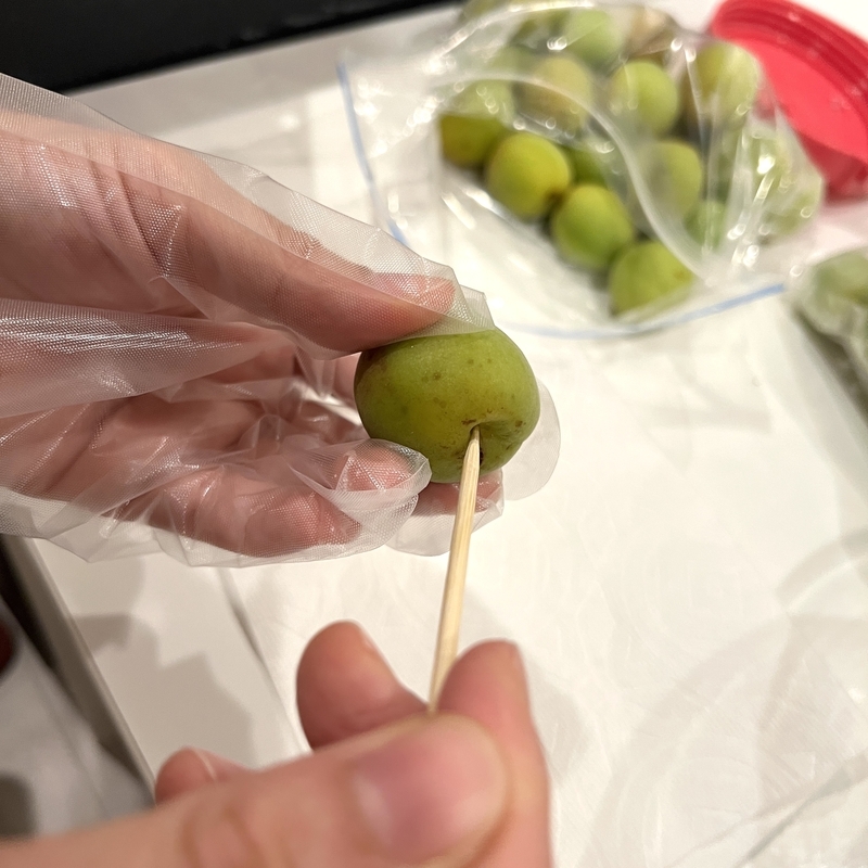 竹串で青梅のへたを丁寧に取り除いている様子