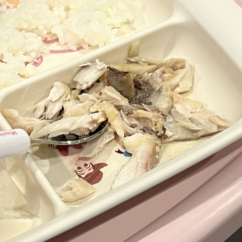 ほぐした味噌煮をのせた子供用のお皿と、スプーンで食べようとする2歳娘の手元。
