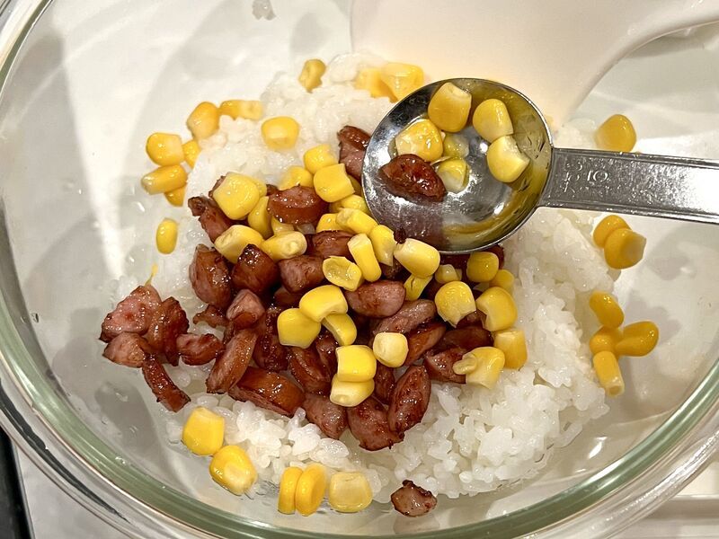 水気を切ったとうもろこしとウインナーをご飯に混ぜている所