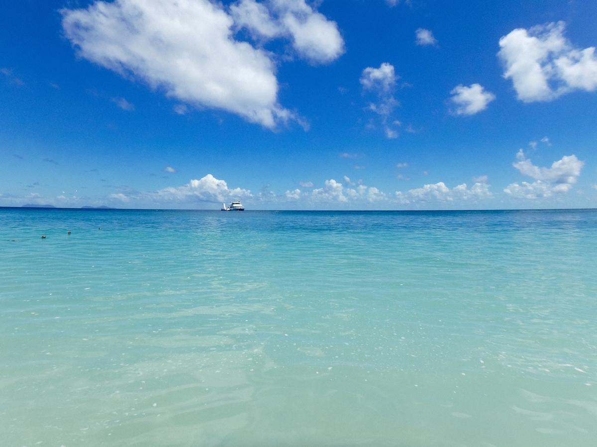 真っ青な海に浮かぶクルーザーのフリー画像（写真）