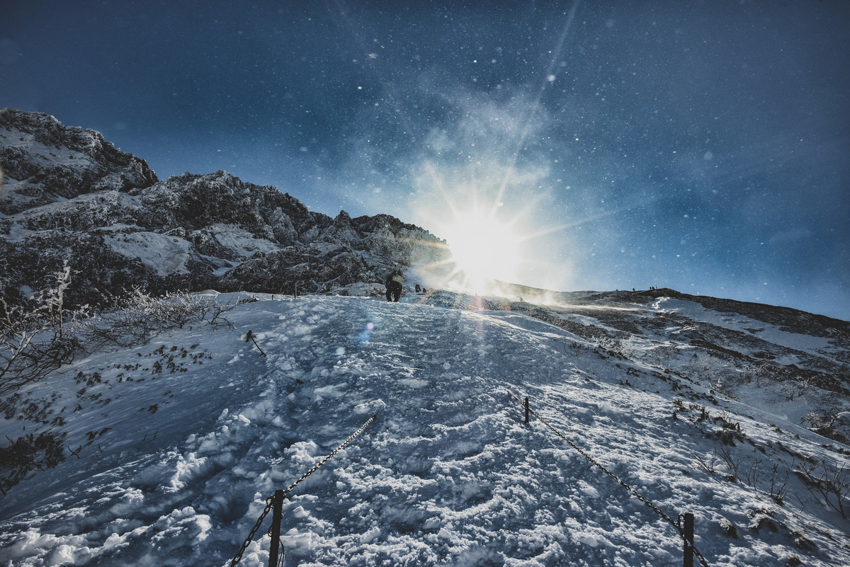 雪煙舞う稜線と登山者のフリー素材（写真）