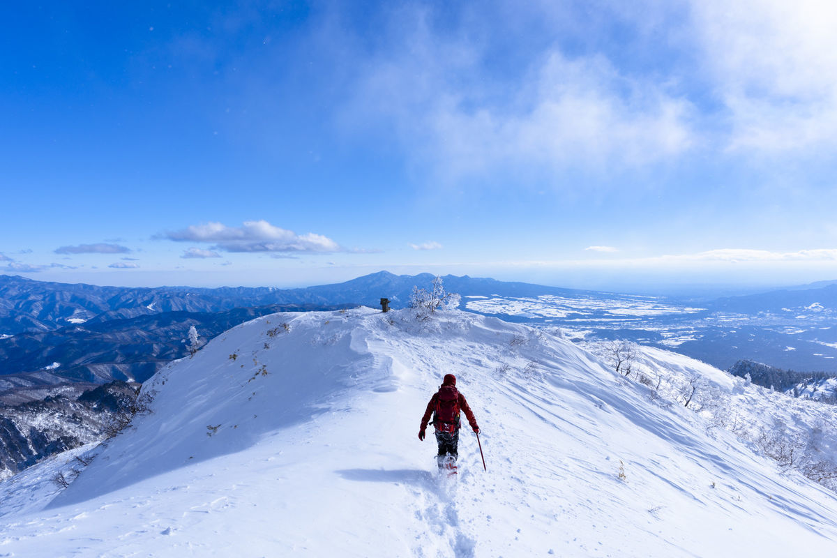 雪原を走る赤い登山者（上州武尊山）の写真素材