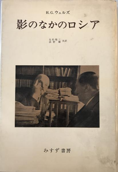"古びた白い表紙の本の表紙写真。中央にH.G.ウェルズと題された白黒写真が配置され、2人の男性が対面で座っている様子が写っている。左の禿げ頭の男性（レーニン）は手を頰に当てて話し、右の男性 (H.G.ウェルズ)は真剣に聞いている。書籍タイトルは『影のなかのロシア』、訳者は生松敬三・浜野稔、出版社はみすず書房と記載されている。"