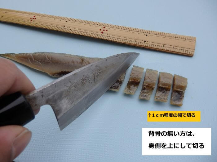 カサゴのエサにするために1ｃｍ程で切り分けているサンマの干物の写真