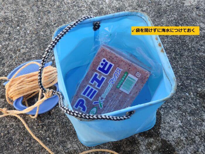 エサのアミエビを溶かすために水汲みバケツにくんだ海水につけている写真