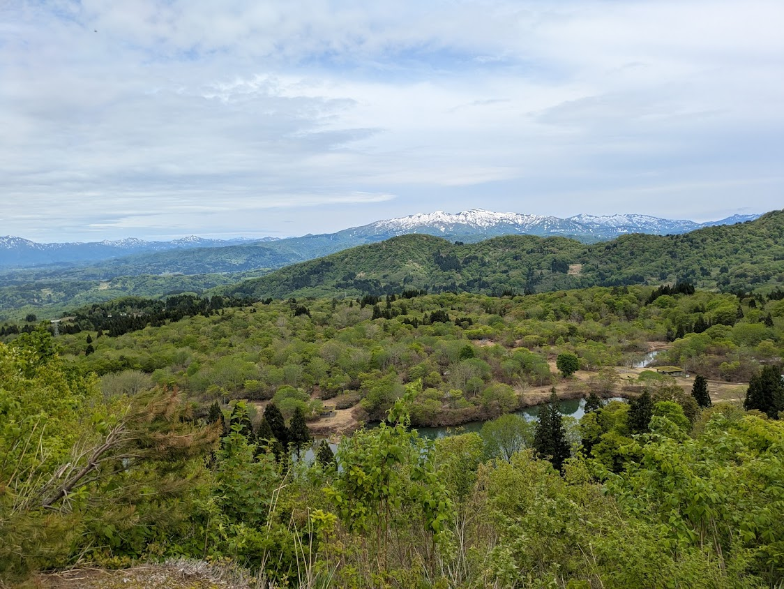 八方台からの風景。下の方に池や森林が、中央に雪を被った岩山が見える。
