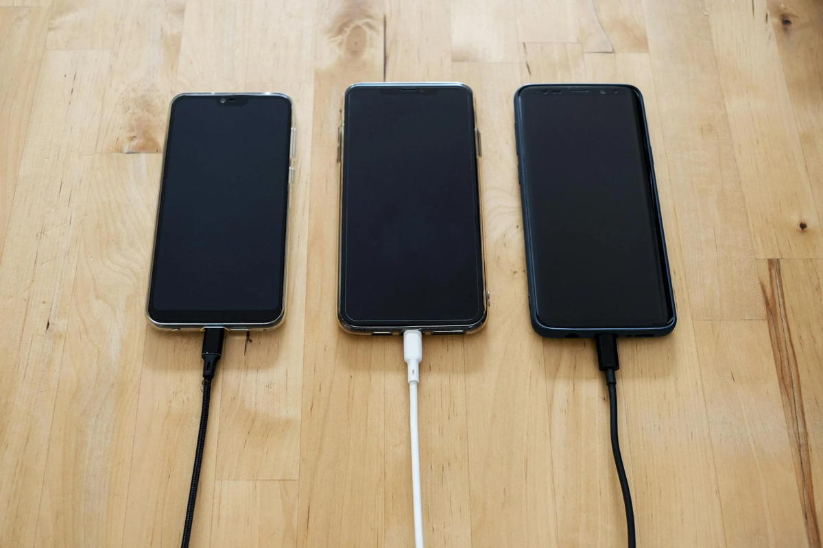 USBで充電されているスマホが3台並んでいる