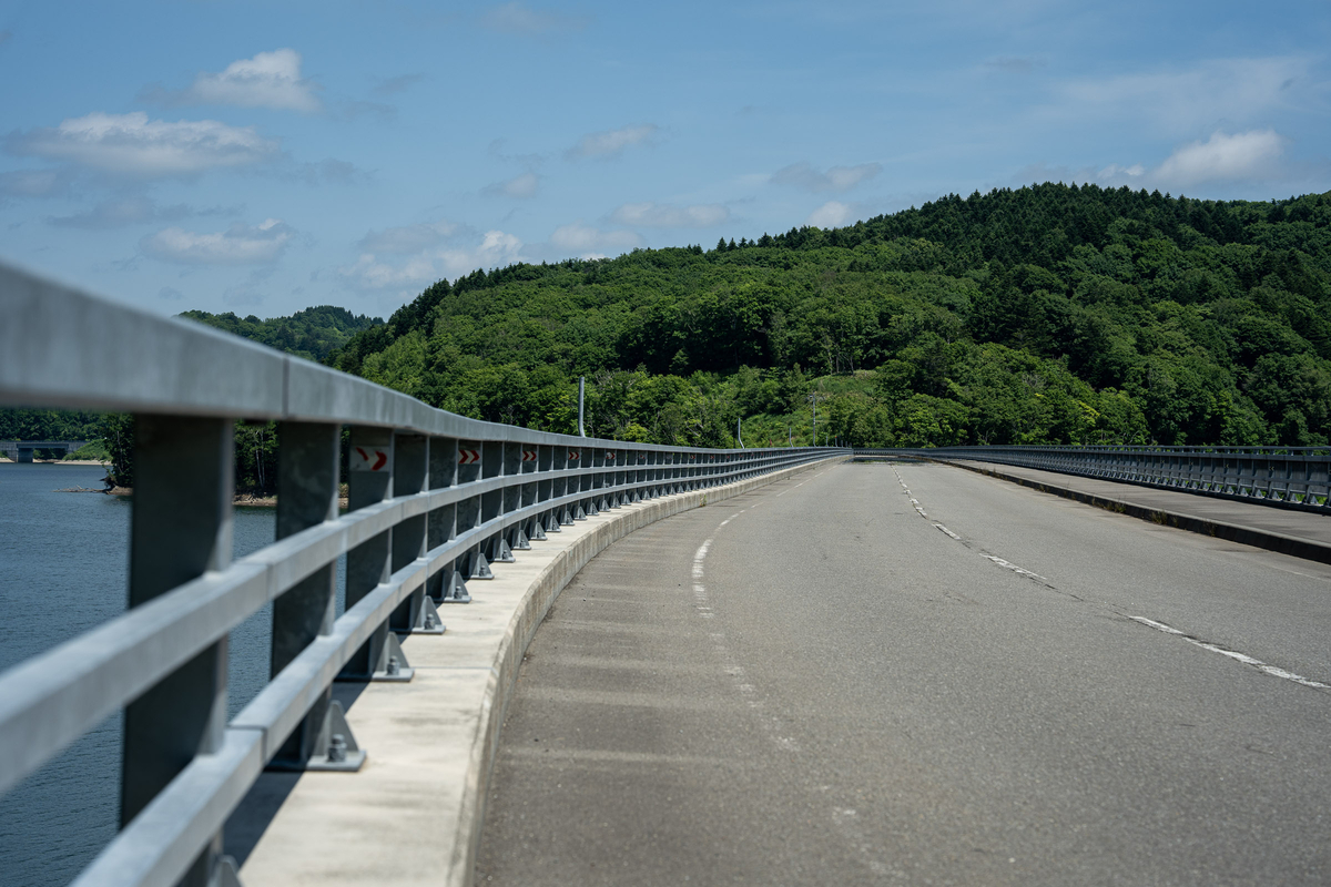 当別ふくろう湖に架かる橋の上から続く道路と緑の山