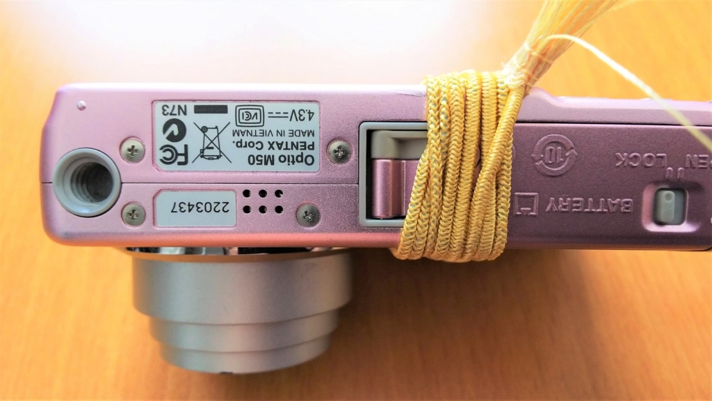 壊れかけのデジカメにゴムを巻き付けて応急処置をした画像