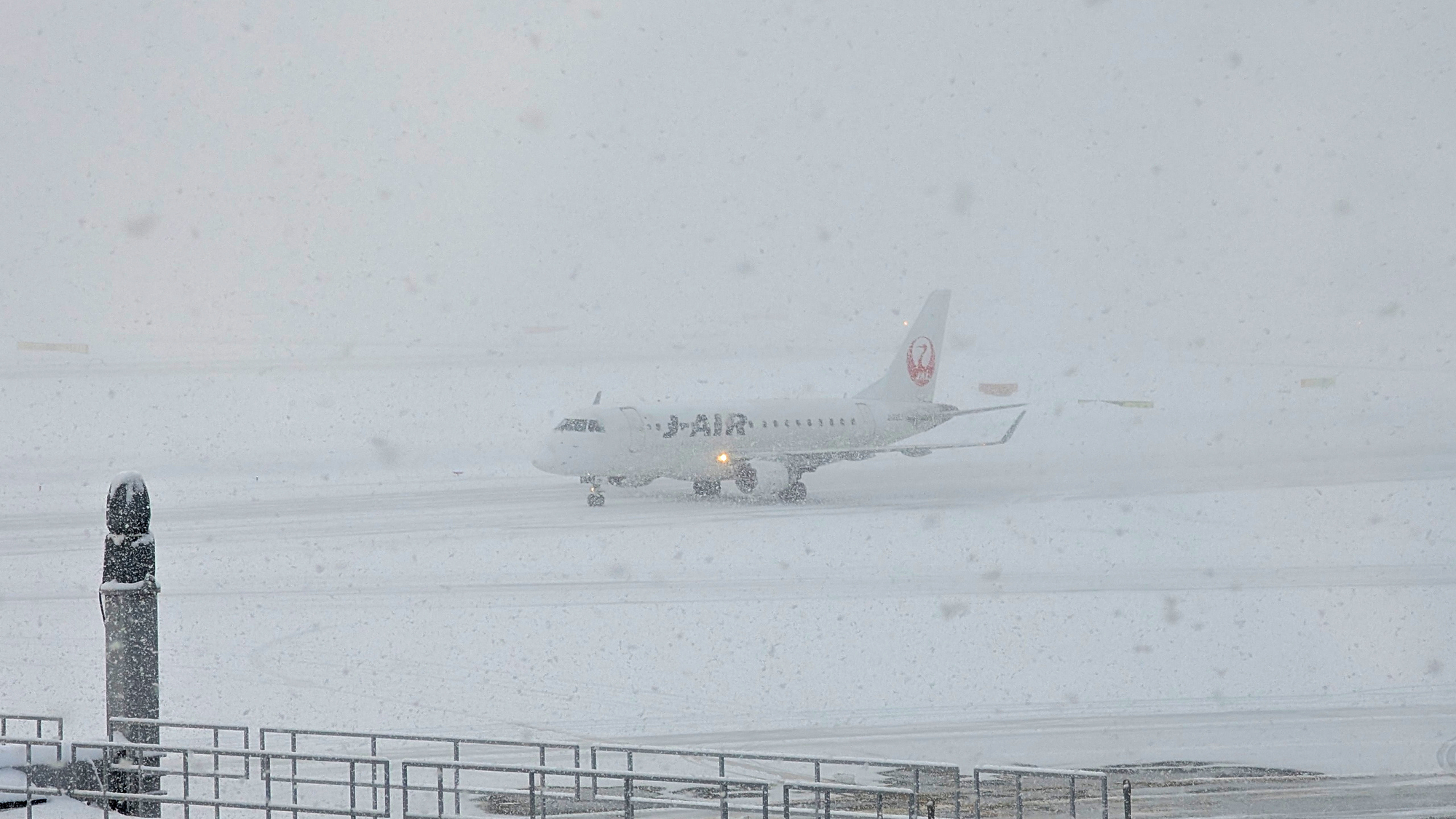 大雪の新千歳空港に着陸し、駐機場へ移動中のJ-AIR E170型機。