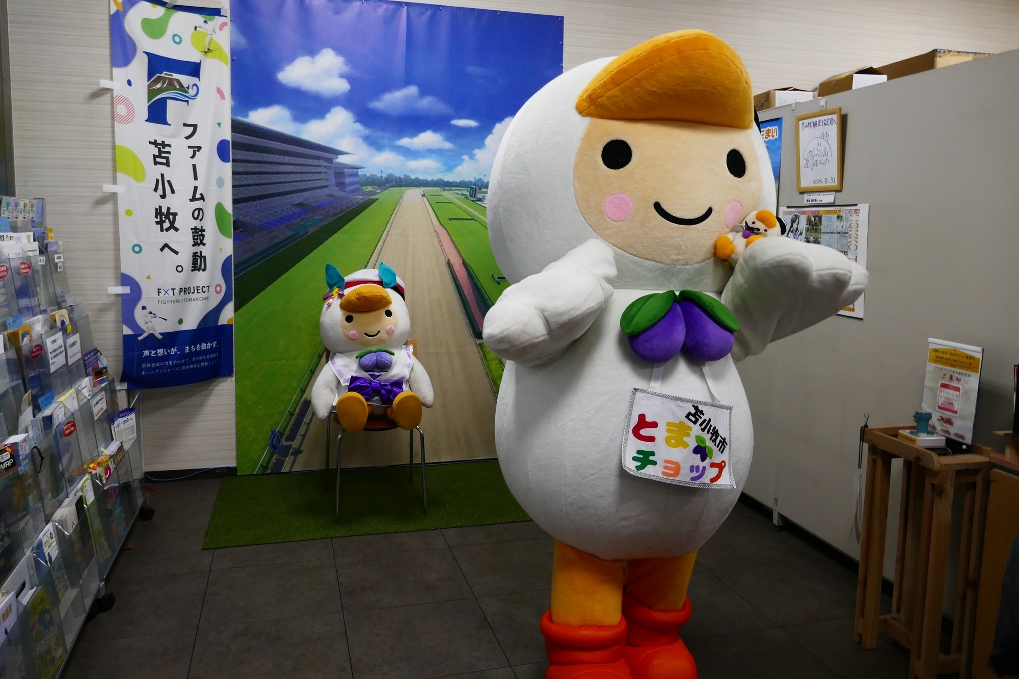 ウマ娘の東京競馬場のタペストリーを背景に、とまチョップを撮影